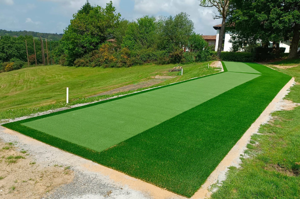 Metro New York Outdoor tee line consisting of one continuous green synthetic grass strip surrounded by trees