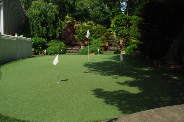 Metro New York Synthetic grass golf green with flags in a landscaped backyard