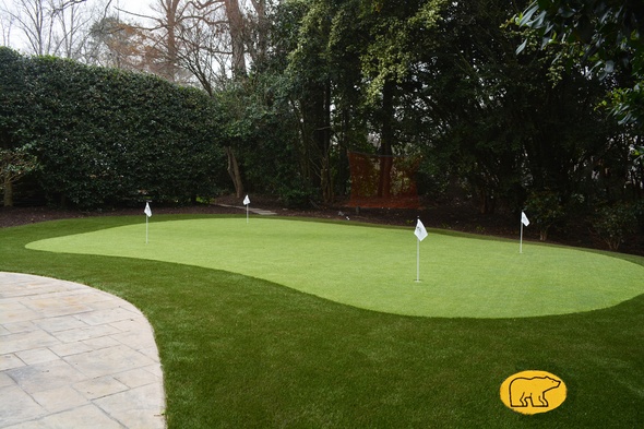 Metro New York Synthetic grass golf green with 4 holes and flags in a landscaped backyard