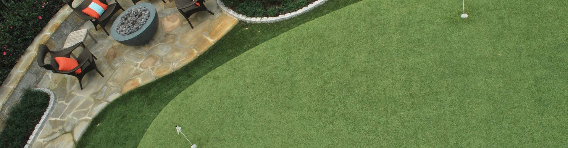 Aerial view of a backyard putting green with two holes, fire pit lounge area, and curved flagstone patio installed by Southwest Greens